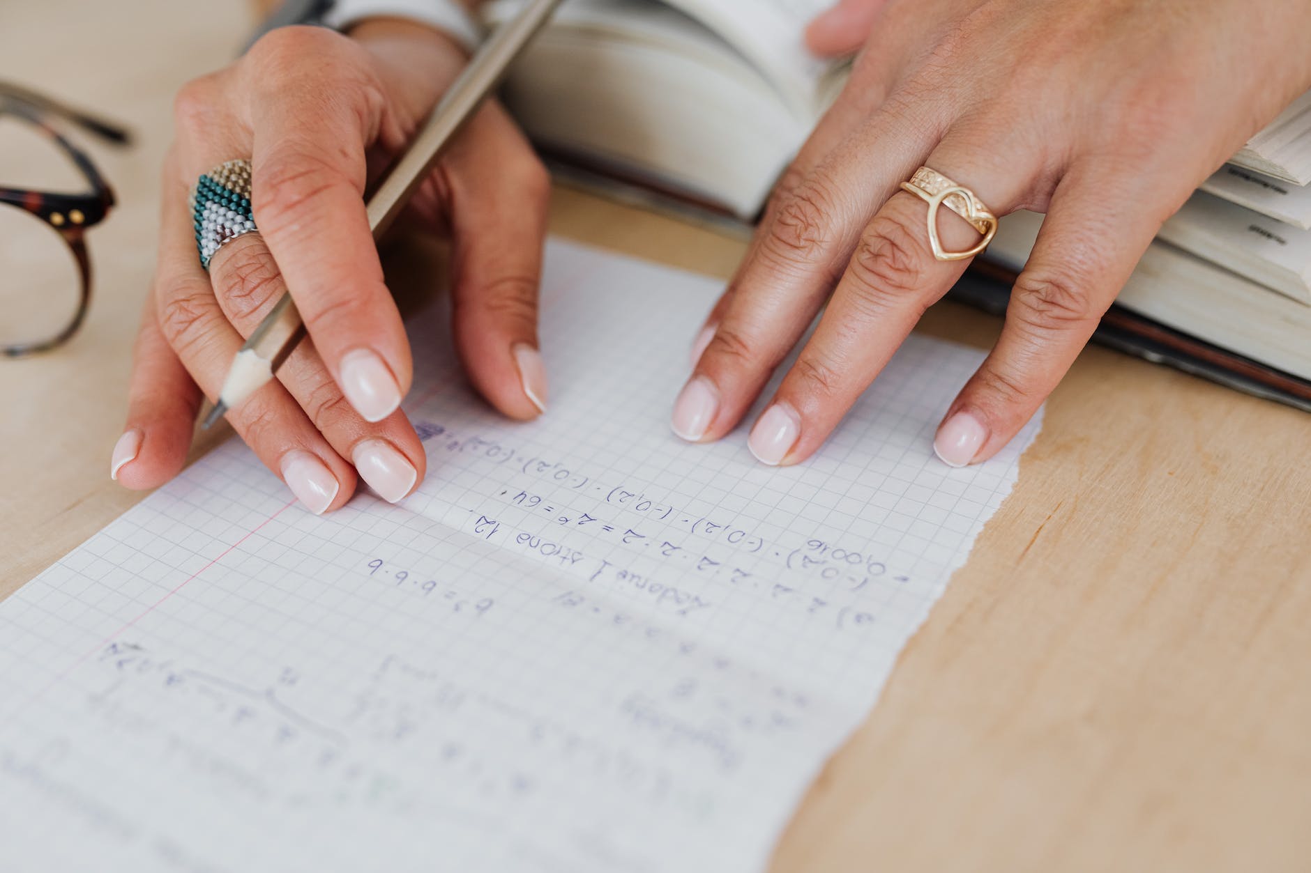 person wearing a gold ring holding a pencil on a graphing paper