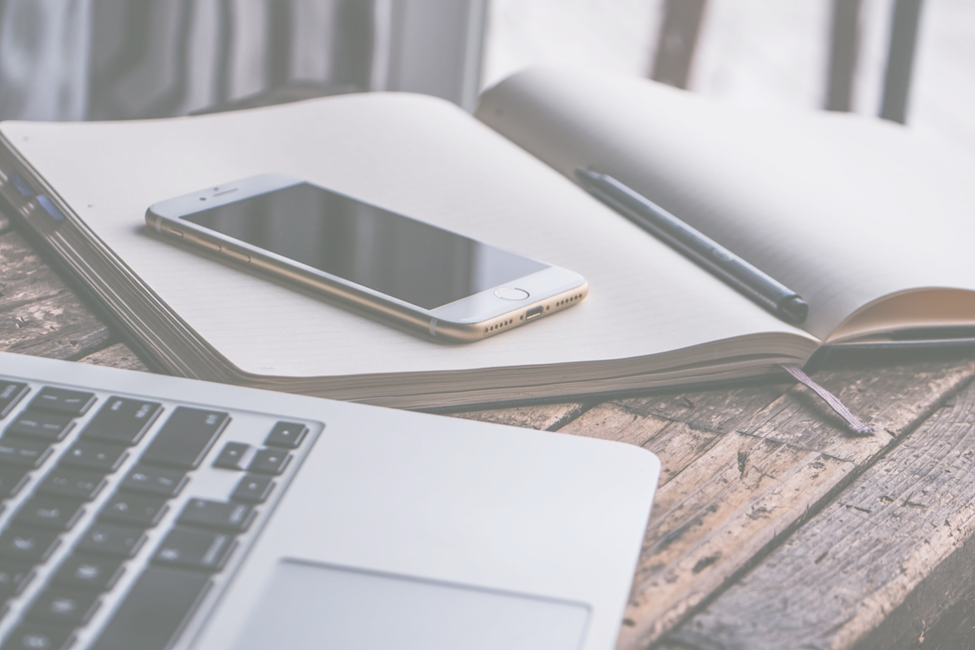 laptop, cellphone and writing tablet on wooden table