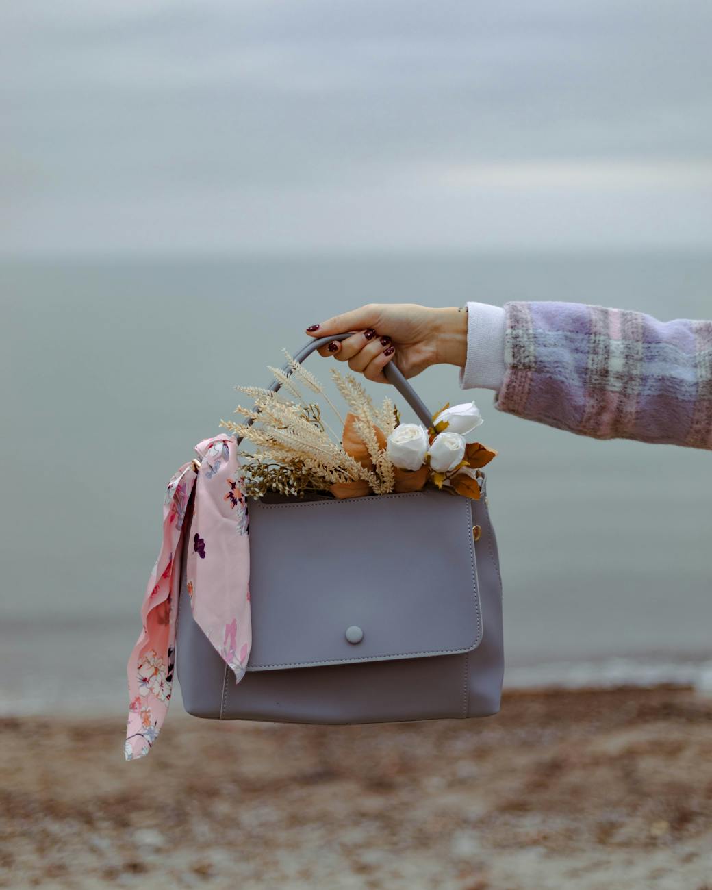 hand holding handbag with bouquet inside